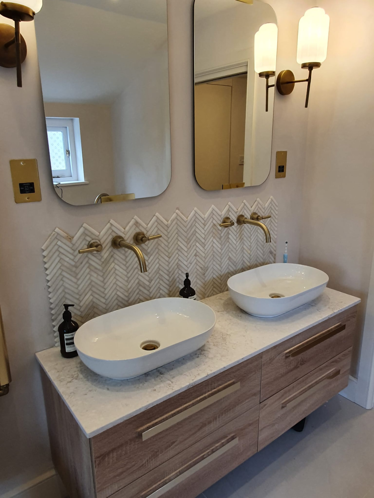 Full bathroom renovation with twin countertop basins, brass wall-mounted taps, herringbone tiling and brass shower by Maxfix in Richmond