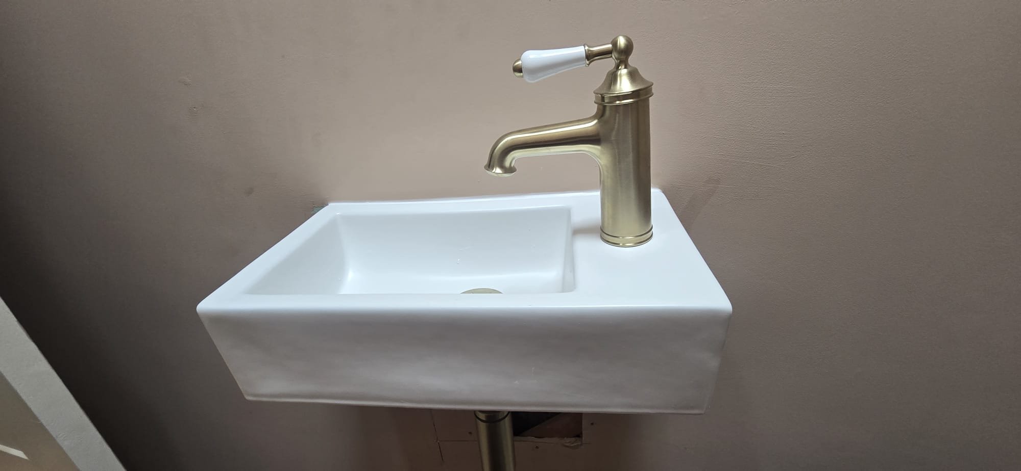 Wall-hung cloakroom basin with brushed brass tap and bottle trap installed by Maxfix in KT5