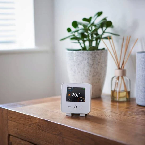 Smart thermostat with colour display on an oak side table in a South West London home